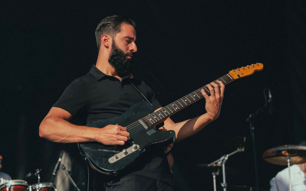 Órale Band guitarist playing at an outdoor festival stage