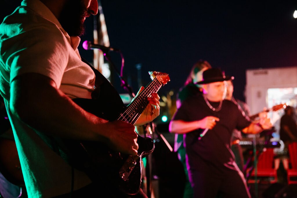 Órale Band guitarist on stage under coloured lights