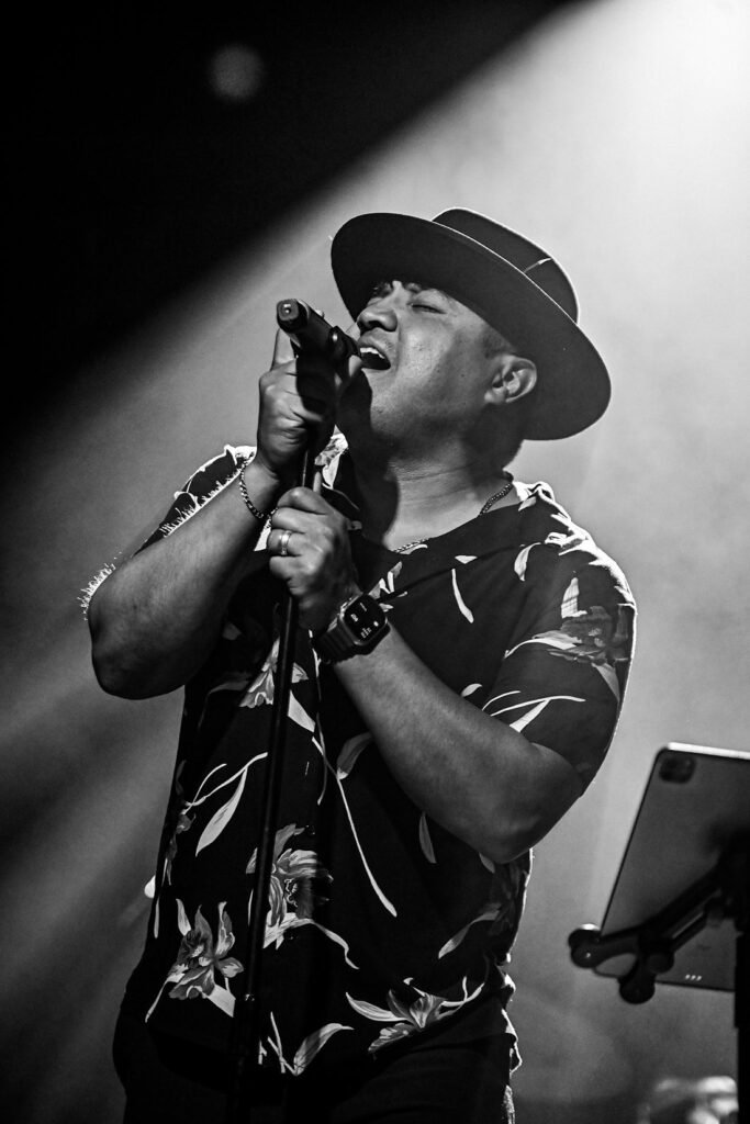Koki singing lead for Órale Band, black and white live stage photo