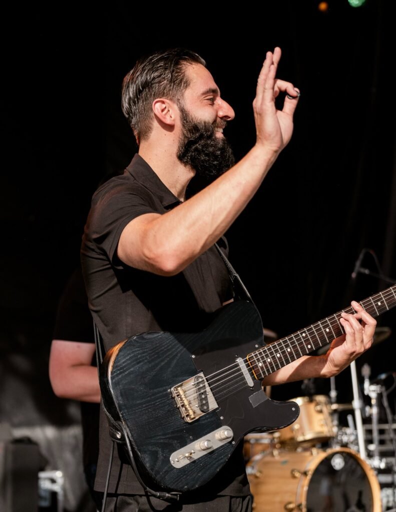 Guitarist performing with Órale Band under stage lights